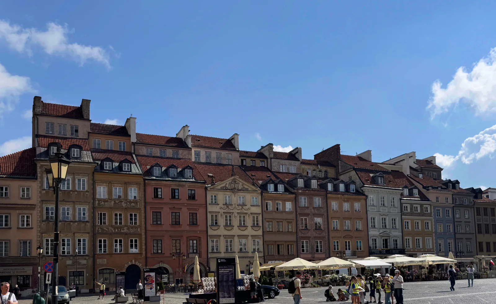 Warsaw's Old Town Market Square, ringed by pastel townhouses and café umbrellas